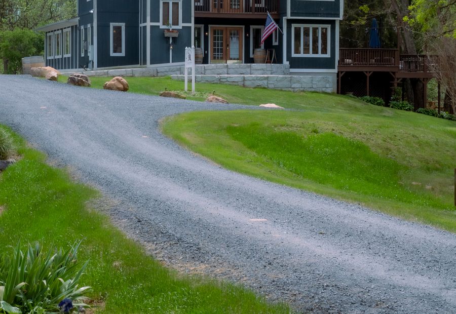 Gravel driveway curving through trees toward a house
